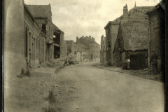 Ruine eines kleinen Dorfes nach dem Krieg, mit beschädigten Gebäuden und einer leeren Straße