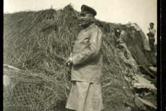 Militärangehöriger in Uniform steht neben einem Heuhaufen auf einem Feld während des Ersten Weltkriegs