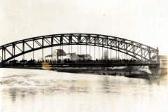 Historische Brücke über einen Fluss mit Menschen und Gebäuden im Hintergrund
