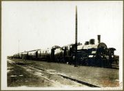 Dampflok am Bahnhof mit Waggons auf den Gleisen in historischem Setting