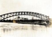 Historische Brücke über einen Fluss mit Menschen und Gebäuden im Hintergrund