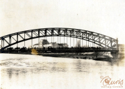 Historische Brücke über einen Fluss mit Menschen und Gebäuden im Hintergrund