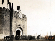 Heer versammelt sich vor historischer Stadtmauer in einem frühen 20. Jahrhundert