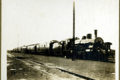 Dampflok am Bahnhof mit Waggons auf den Gleisen in historischem Setting