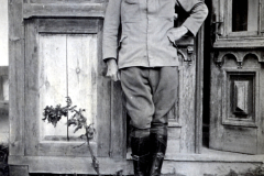 Ein Soldat in Uniform steht neben einer historischen Tür, umgeben von ländlicher Architektur