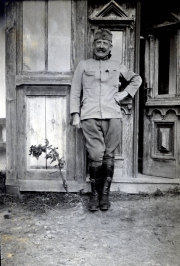 Ein Soldat in Uniform steht neben einer historischen Tür, umgeben von ländlicher Architektur