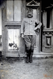 Ein Soldat in Uniform steht neben einer historischen Tür, umgeben von ländlicher Architektur