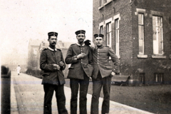 Drei Soldaten der Heer im frühen 20. Jahrhundert vor einem historischen Gebäude in Deutschland