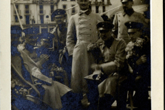 Militärangehörige posieren auf einem Schiff in historischer Kulisse mit Blumen
