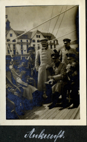 Militärangehörige posieren auf einem Schiff in historischer Kulisse mit Blumen