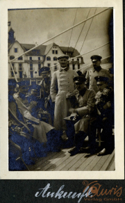 Militärangehörige posieren auf einem Schiff in historischer Kulisse mit Blumen
