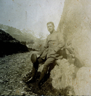 Soldat sitzt entspannt an einer Felswand in den Alpen während des Ersten Weltkriegs