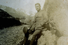 Soldat sitzt entspannt an einer Felswand in den Alpen während des Ersten Weltkriegs