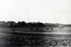 Historische Landschaft mit landwirtschaftlichen Feldern und alten Gebäuden in der Nähe eines kleinen Dorfes