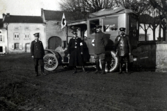 Heerangehörige posieren neben einem historischen Fahrzeug in einer ländlichen Umgebung