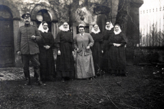 Gruppenbild von Soldaten und Nonnen vor historischem Hintergrund im frühen 20. Jahrhundert