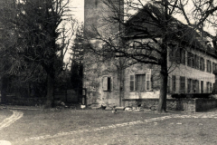 Historisches Gebäude mit Turm und Baumlandschaft in einer ländlichen Umgebung