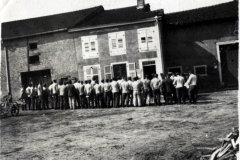 Menschen versammeln sich vor einem Gebäude in einem ländlichen Gebiet während eines historischen Ereignisses