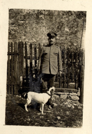 Soldat steht mit seinem Hund vor einem Zaun auf einem historischen Gelände
