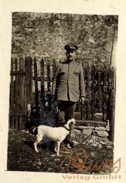 Soldat steht mit seinem Hund vor einem Zaun auf einem historischen Gelände