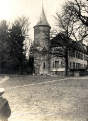 Historisches Gebäude mit Turm und Baumlandschaft in einer ländlichen Umgebung