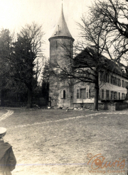 Historisches Gebäude mit Turm und Baumlandschaft in einer ländlichen Umgebung