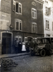 Menschen auf einer Straße vor einem Gebäude mit einem alten Auto in einer historischen Stadt