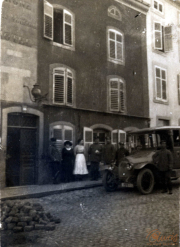 Menschen auf einer Straße vor einem Gebäude mit einem alten Auto in einer historischen Stadt