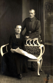 Portrait eines Soldaten in Uniform mit einer Frau auf einem Sofa vor neutralem Hintergrund in einem historischen Setting