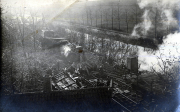 Historische Bahnhofsanlage mit dampfbetriebenem Zug und Arbeiter im Schatten von Bäumen