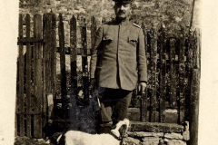 Soldat steht mit seinem Hund vor einem Zaun auf einem historischen Gelände