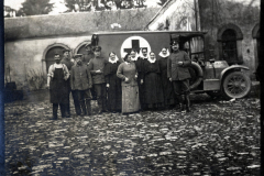 Medizinisches Personal und Soldaten vor einem Sanitätsfahrzeug während des Ersten Weltkriegs in einer historischen Umgebung