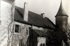 Ein historisches Herrenhaus mit Aussichtsturm umgeben von Natur im frühen 20. Jahrhundert