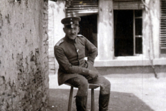 Soldat der Heer auf einem Hocker vor einem alten Gebäude in einer ländlichen Umgebung