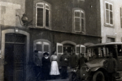 Menschen auf einer Straße vor einem Gebäude mit einem alten Auto in einer historischen Stadt