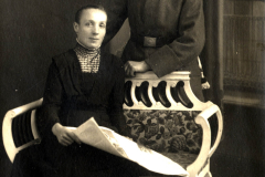 Portrait eines Soldaten in Uniform mit einer Frau auf einem Sofa vor neutralem Hintergrund in einem historischen Setting