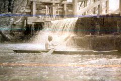 Ein Junge paddelt in einem Kanu am Wasserkraftwerk des IV. Thüringischen Infanterieregiments 72