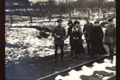 Soldaten und Zivilisten auf einem Schienenweg im Winter
