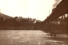 Zerstörte Eisenbahnbrücke über Fluss mit provisorischer Holzkonstruktion im Ersten Weltkrieg