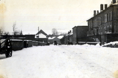 Verschneite Dorfstra?e mit mehrst?ckigen Geb?uden und Kirchturm im Winter