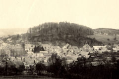 Dorfansicht in Frankreich mit Kirche und bewaldeten Hügeln im Hintergrund