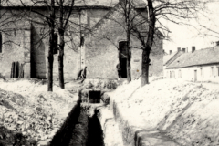 Schützengräben durch französisches Dorf mit Kirche und Wohnhäusern im Hintergrund