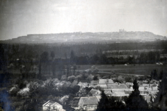 Blick über französisches Dorf mit bewaldeten Hügeln im Hintergrund
