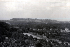 Landschaftsaufnahme einer französischen Ortschaft mit Kirchenruine und bewaldeten Hügeln