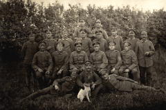 Gruppenfoto deutscher Soldaten des Infanterie-Regiments 53 mit Hund vor Hecke