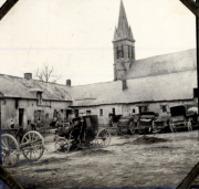 Dorfplatz mit Militärfahrzeugen und Kirchturm in französischem Ort während des Ersten Weltkriegs