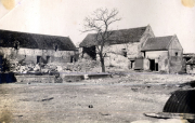 Zerstörte Dorfhäuser mit Trümmerschutt und kahlem Baum in französischem Kriegsgebiet