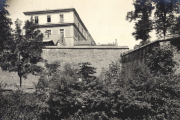 Mehrstöckiges Gebäude mit Steinmauer und Vegetation in französischer Ortschaft