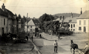 Marktplatz eines französischen Dorfes mit deutschen Soldaten und Militärfahrzeugen