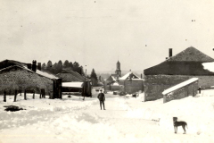 Verschneite Dorfszene mit Kirche und Steingebäuden im Winter